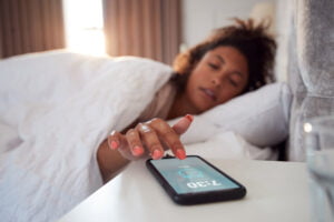 Woman waking up and reaching for phone