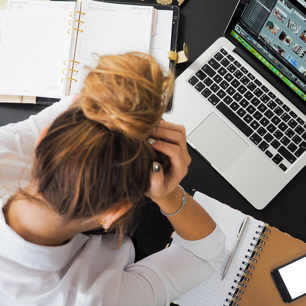 Blonde woman with laptop and notes, frustrated