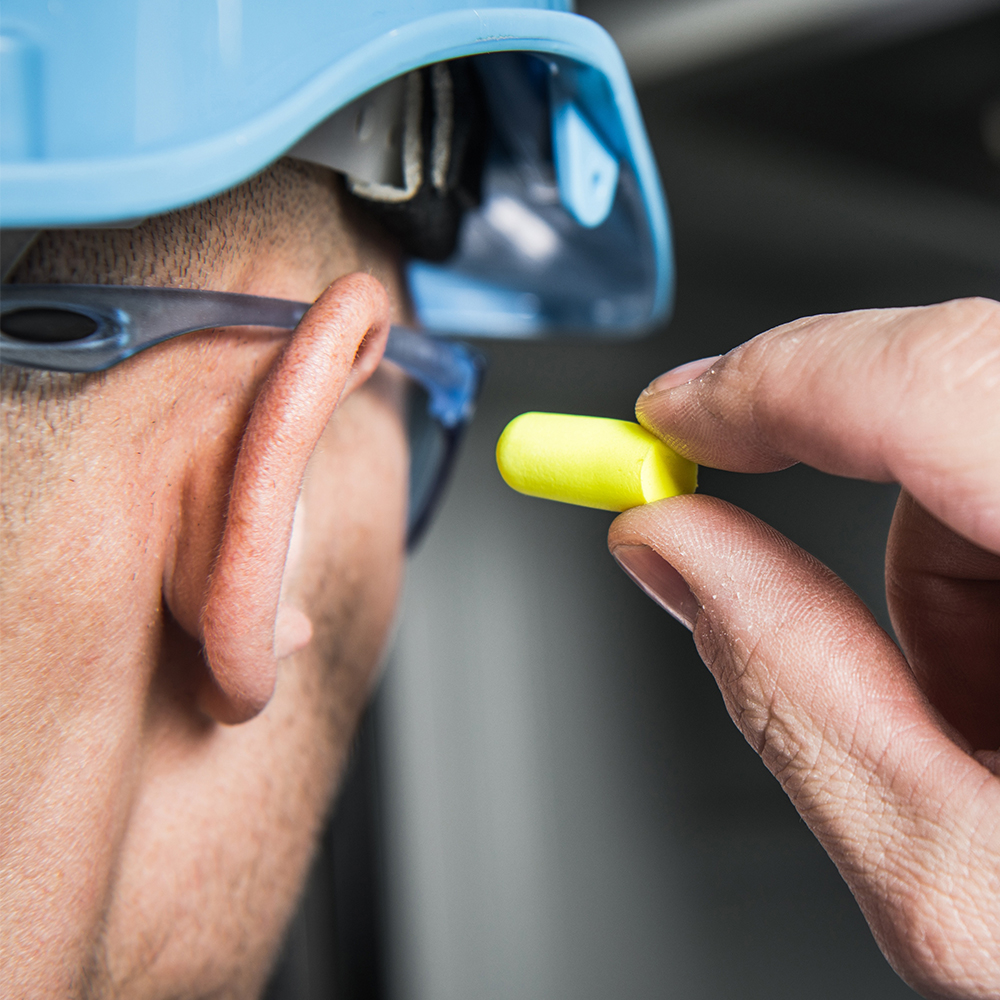 Construction worker inserting ear mould into ear