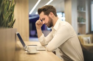 Frustrated-looking male employee sitting at desk in front of laptop