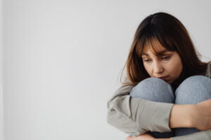 Depressed-looking woman sitting on floor in fetal position