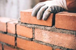 Gloved hand placing a brick on top of other bricks