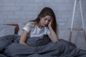 Brown haired woman sitting in bed appearing depressed