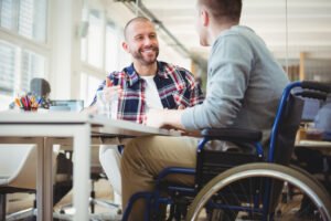 Disabled employee in wheelchair speaking to colleague