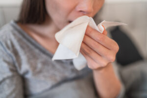Woman holding tissue in front of mouth