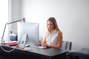 Female employee at her desk typing on computer keyboard
