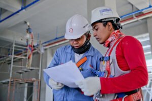 Workers wearing protective equipment, looking at sheet of paper (presumably health and safety policy)