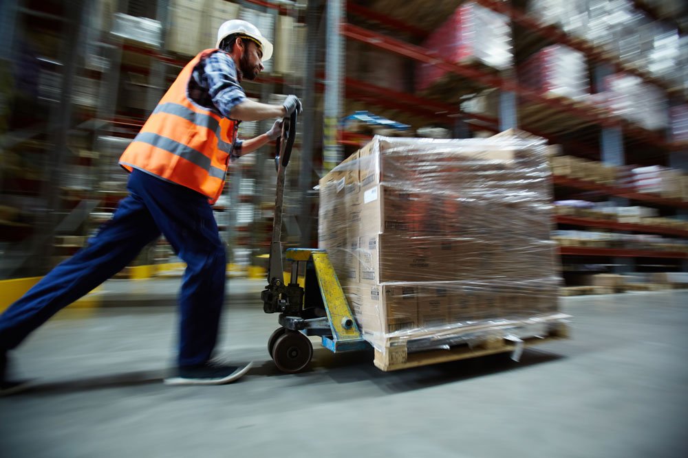 Warehouse employee pushing forklift 