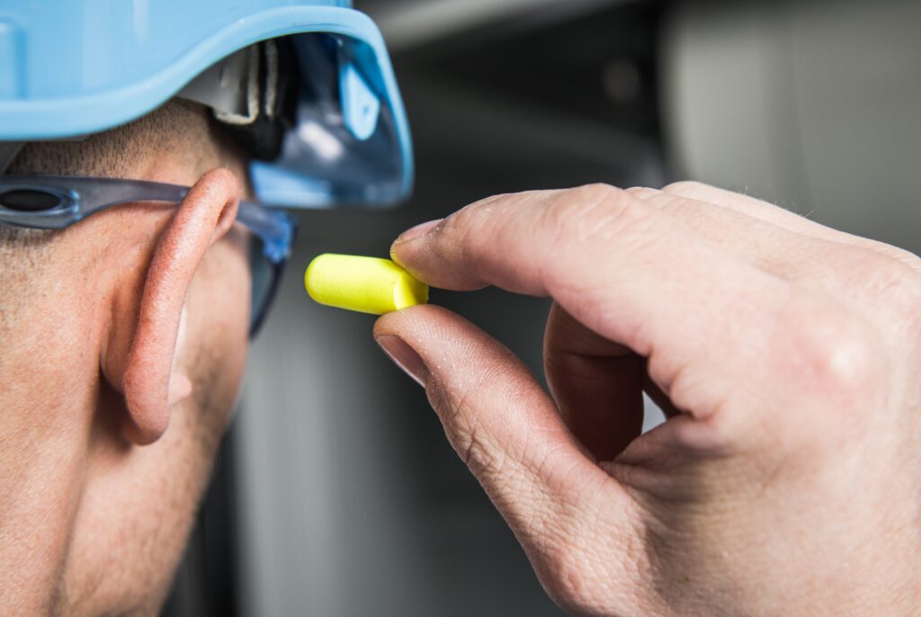 Warehouse/construction/factory worker inserting hearing protection in right ear