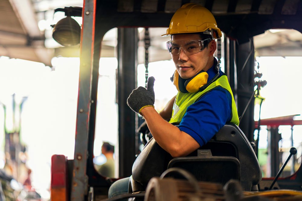 Male warehouse employee driving a forklift 