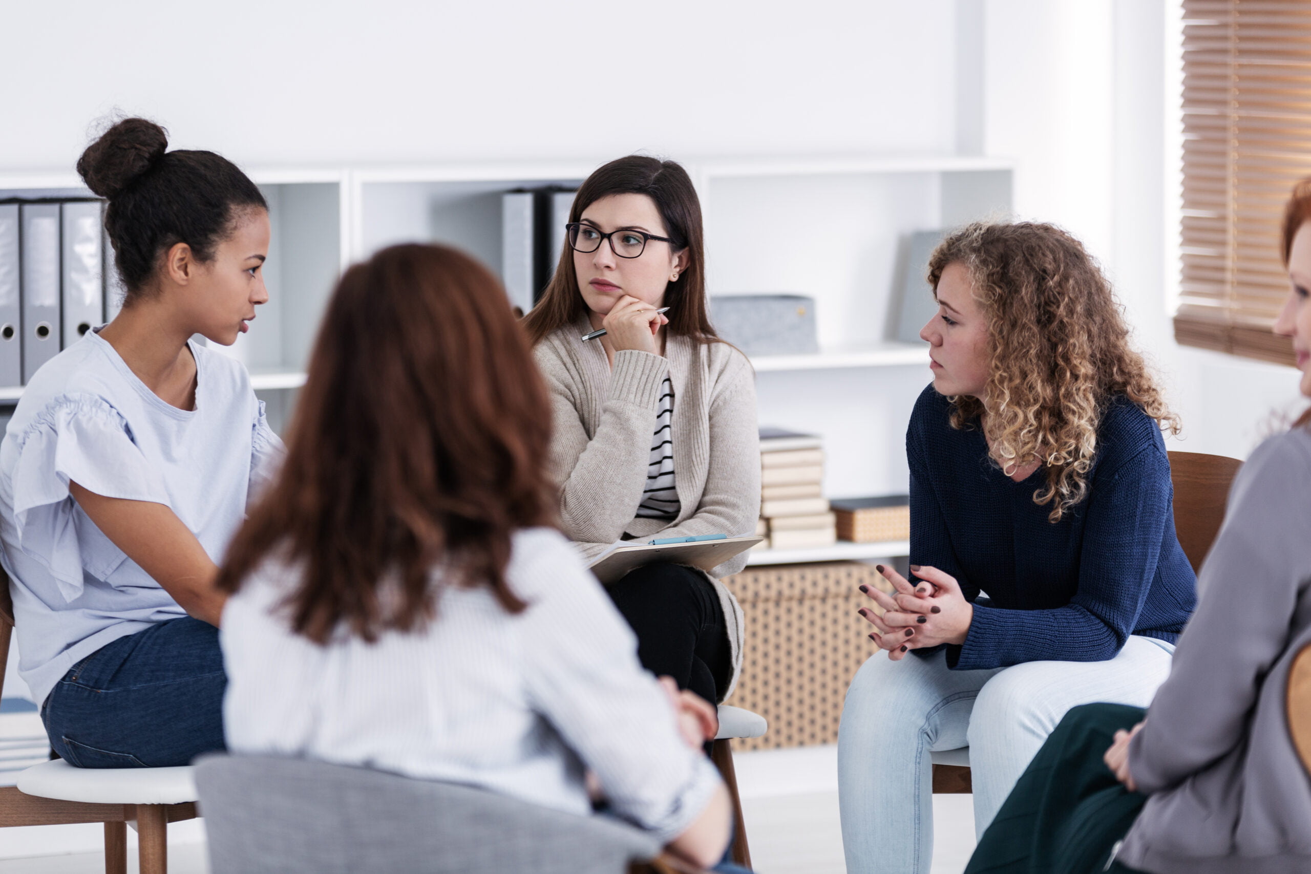 A group of women sitting in a circle, having a group discussion.