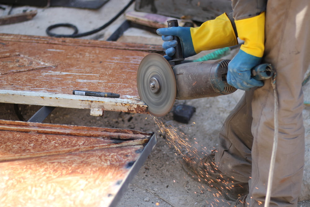 Close-up of construction employee using a tool to cut metal