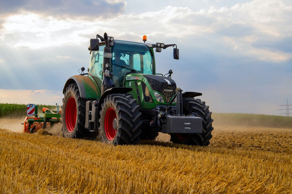 Tractor/harvester with farmer inside, field and grey-white sky in background