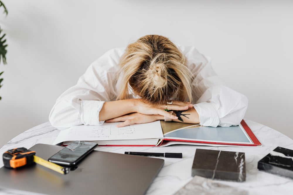 Frustrated female employee lying her head down on a pile of documents