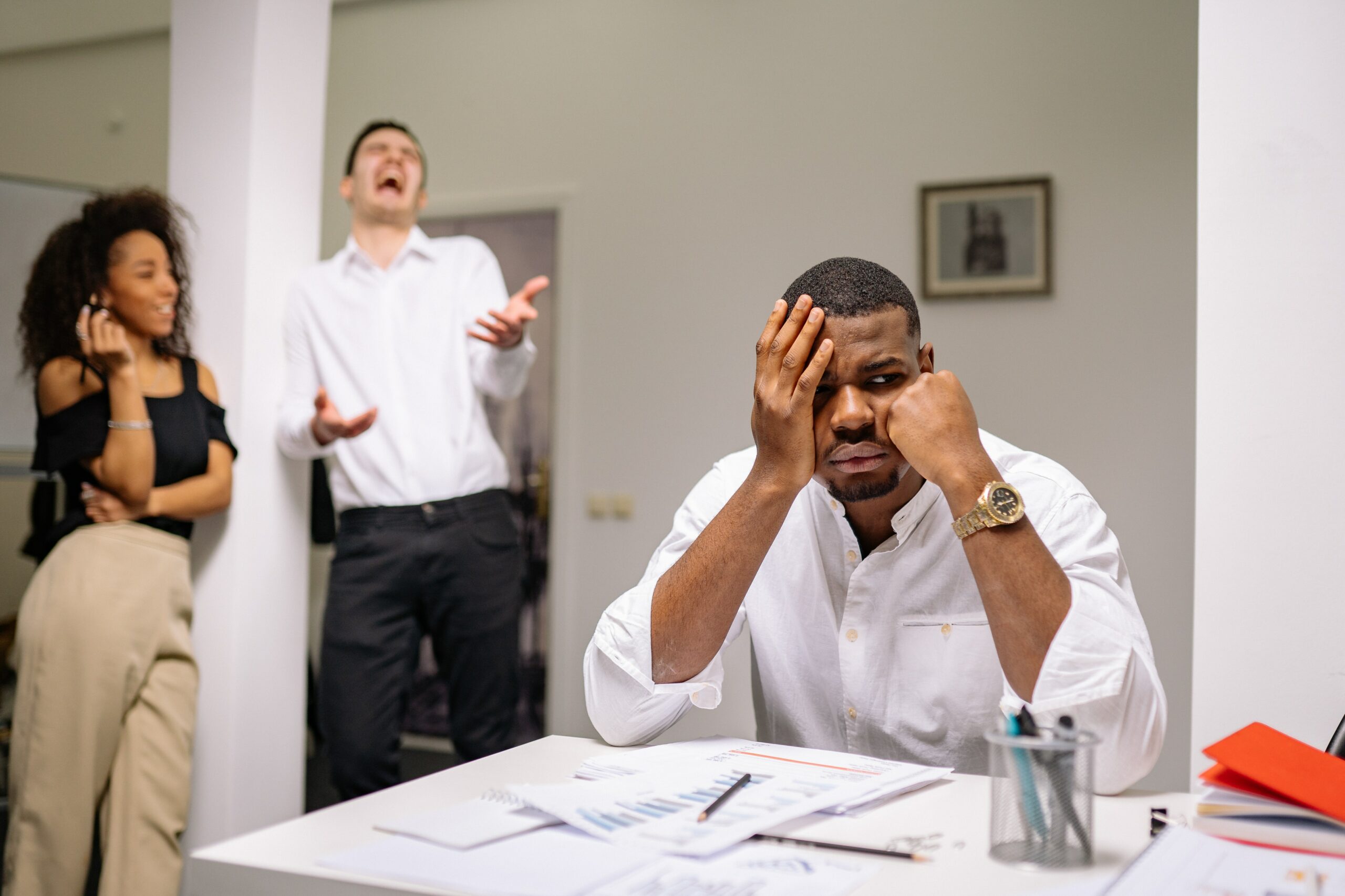 Frustrated- looking employee becoming victim to bullying by two other employees