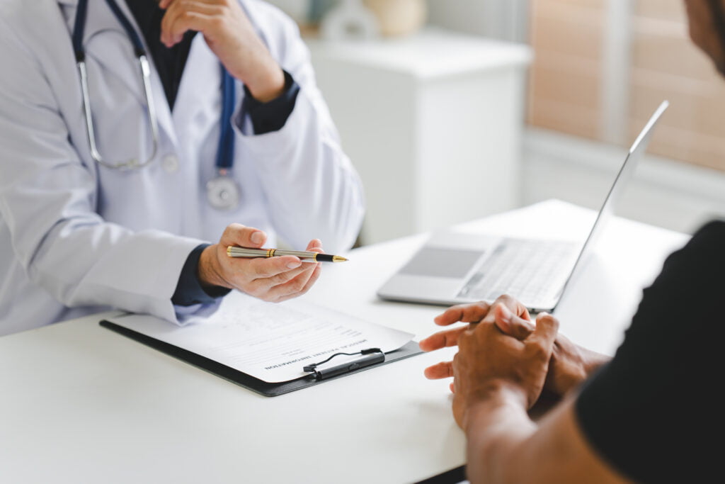 Doctor and patient having a discussion, doctor filling out documents.