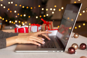 Female hands working on laptop, X-mas decorations in background.