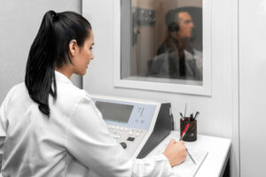 Brunette female occupational health technician performing a hearing test on a middle-aged male