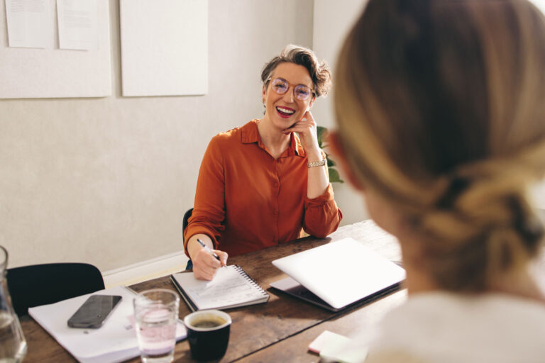 a lady smiling and lady with her back to camera (returning to work meeting)
