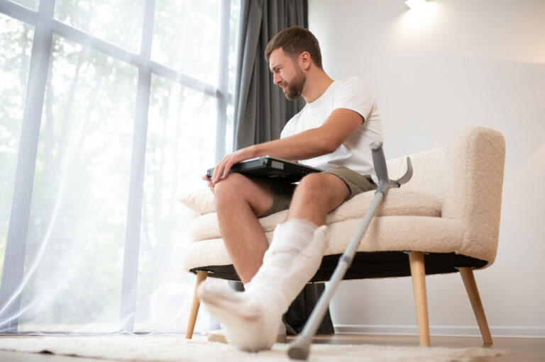 guy with cast on his leg working from home after fit for work assessment