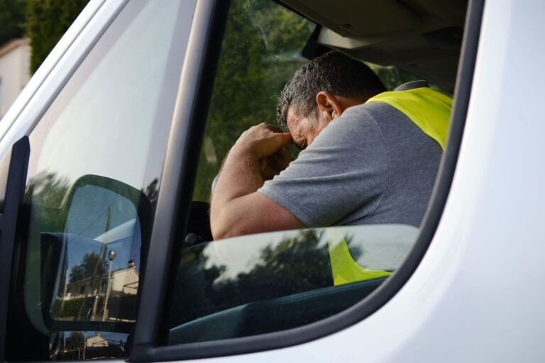a man driver with his head down on steering.