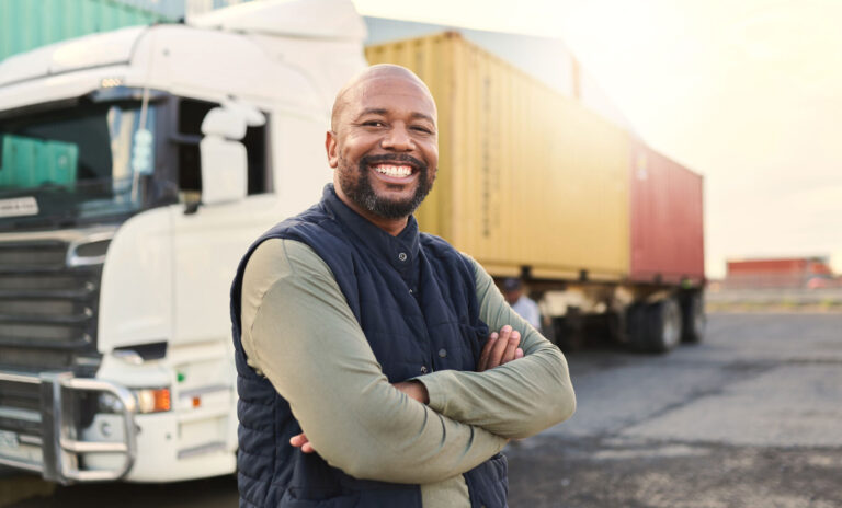 a man standing in front of a truck with his arms folded
